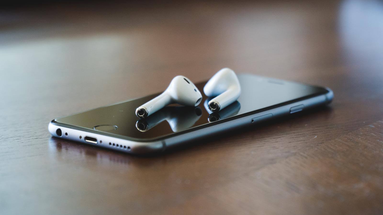 An iPhone and Air Pods on a table.