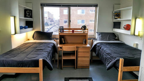 Two beds and a desk in front of a window.