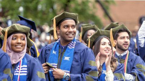 A row of doctoral graduates standing at commencement.