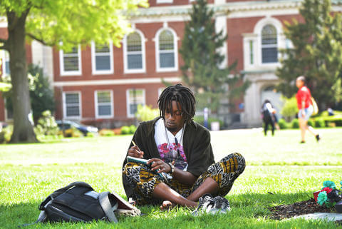 A young man writing in his notebook on The Yard.